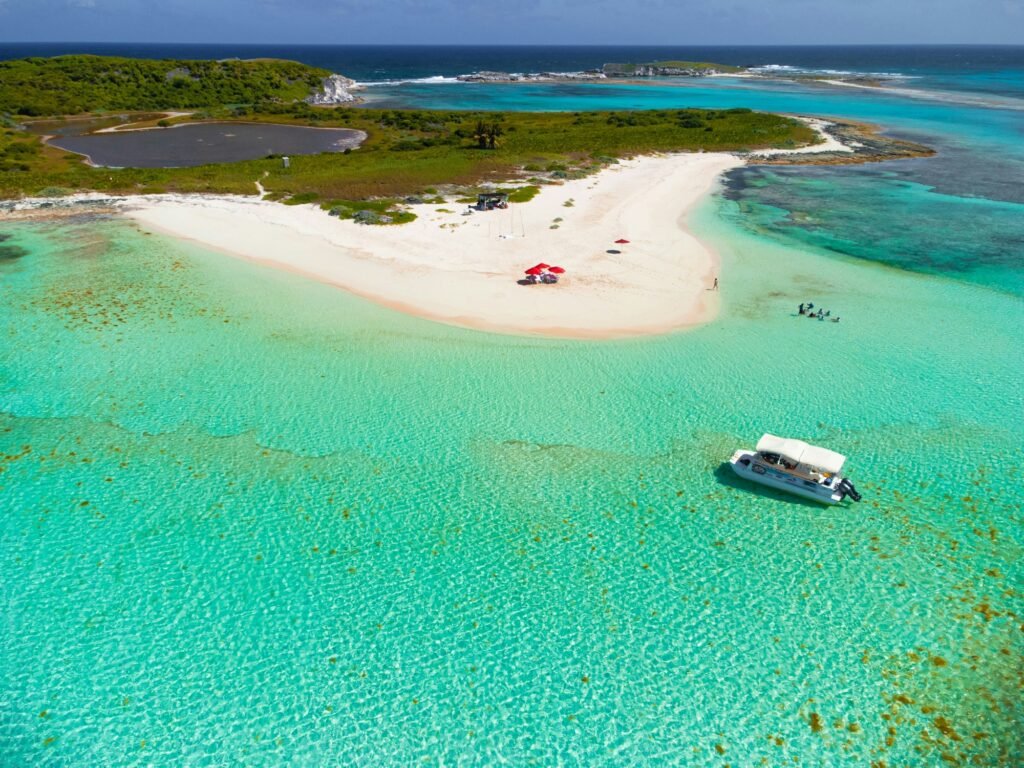 Aerial view of a boat in turquoise sea against a beautiful beach in San Salvador, The Bahamas